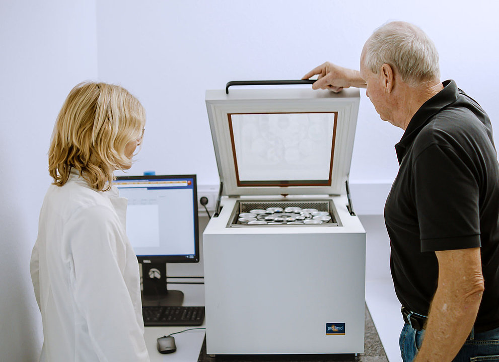 Zwei Personen stehen vor einem SPS Gerät. Die rechte Person öffnet gerade den Deckel