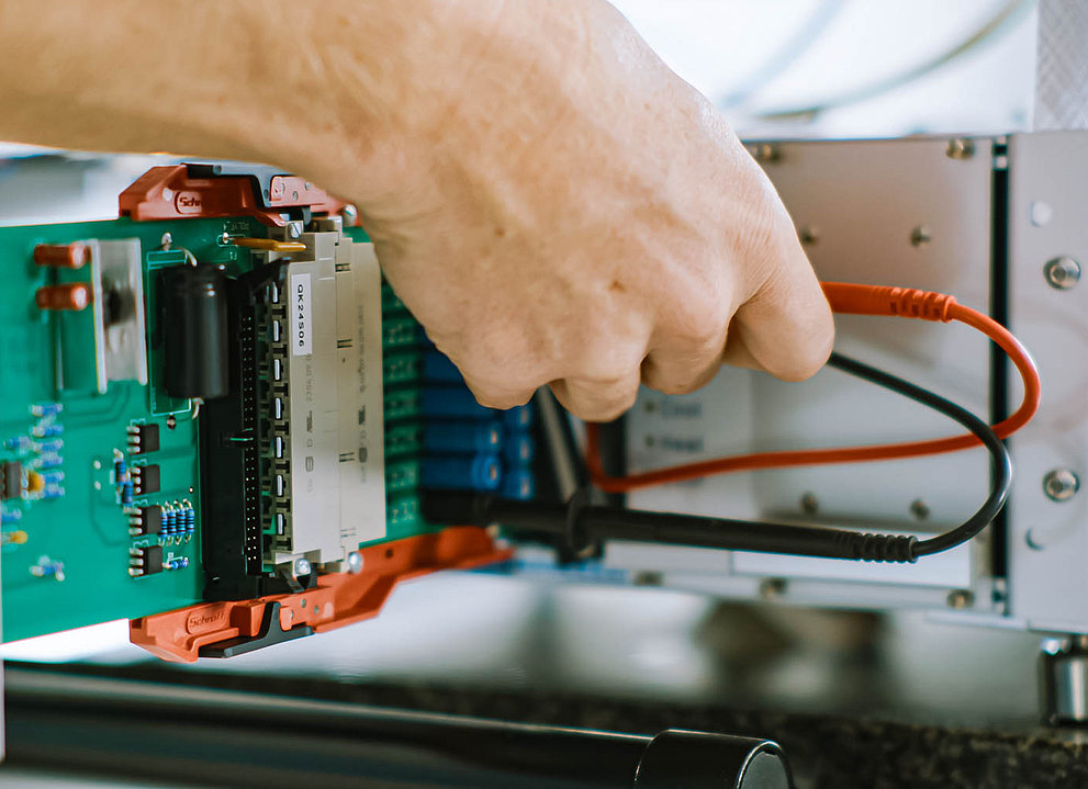 Elektrisches Gerät. Eine Hand steckt Kabel ein