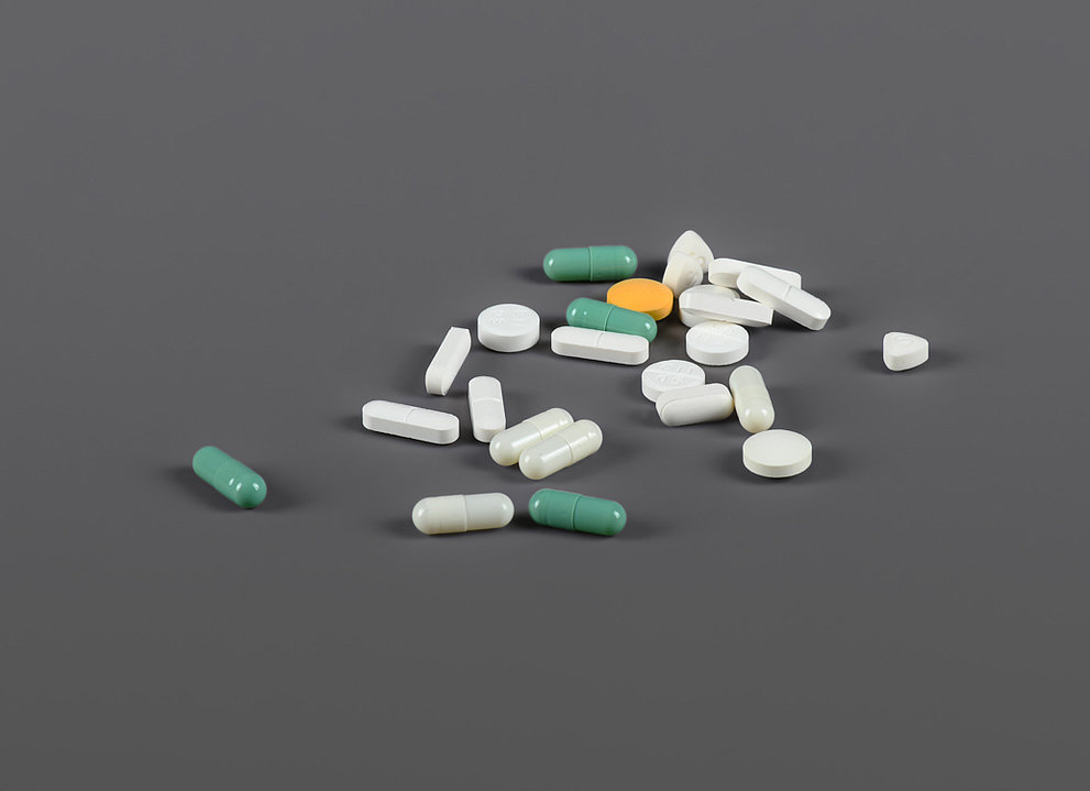 Pillen und Tabletten verstreut auf grauem Hintergrund