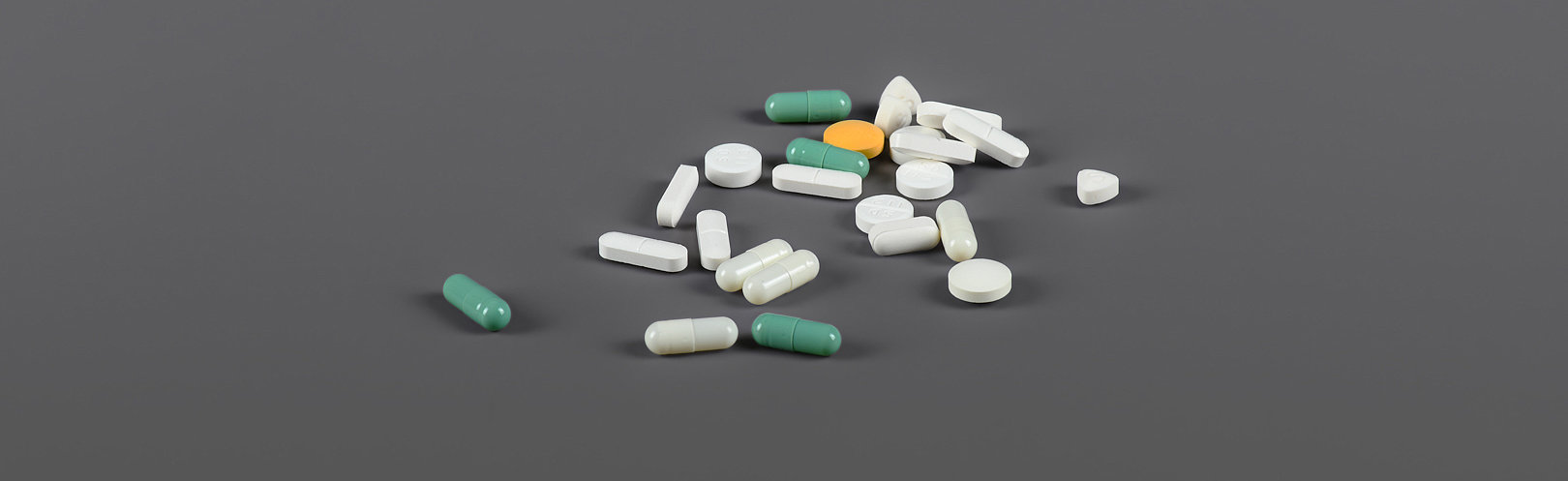 Pillen und Tabletten verstreut auf grauem Hintergrund