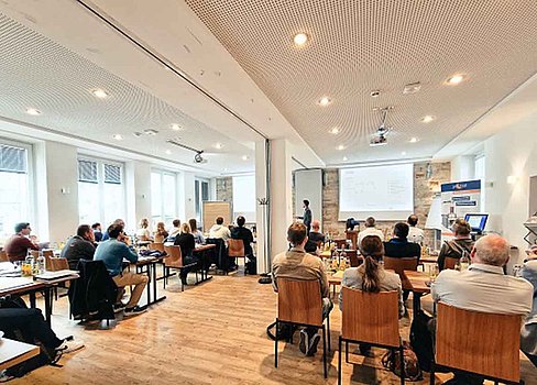 Seminar-Teilnehmer in modernem Konferenzraum mit heller Ausstattung